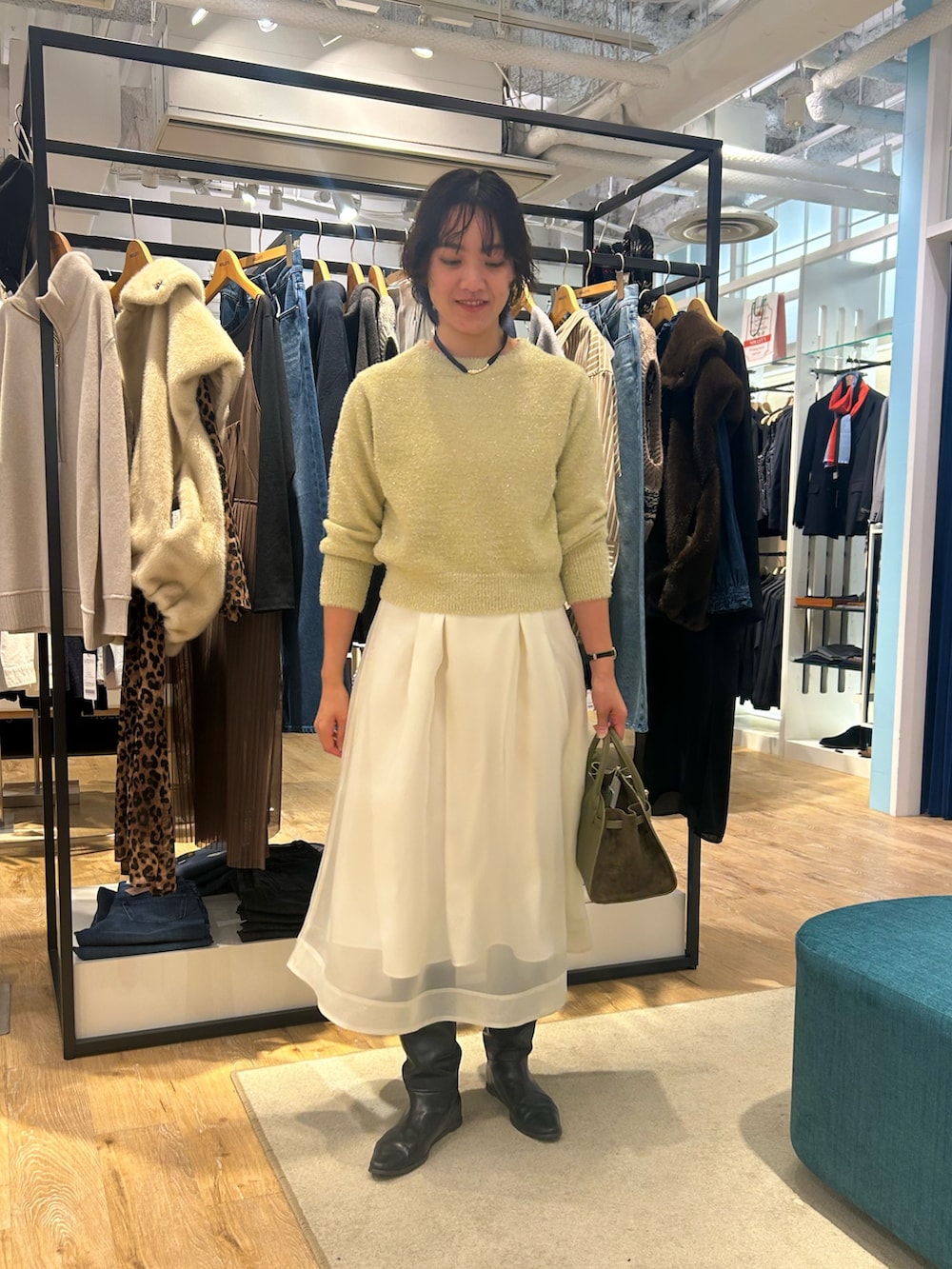 ホワイト系のスカート、イエロー系のニット/セーター、グリーン系のトートバッグを着用したレディースの冬コーディネートの2枚目の写真