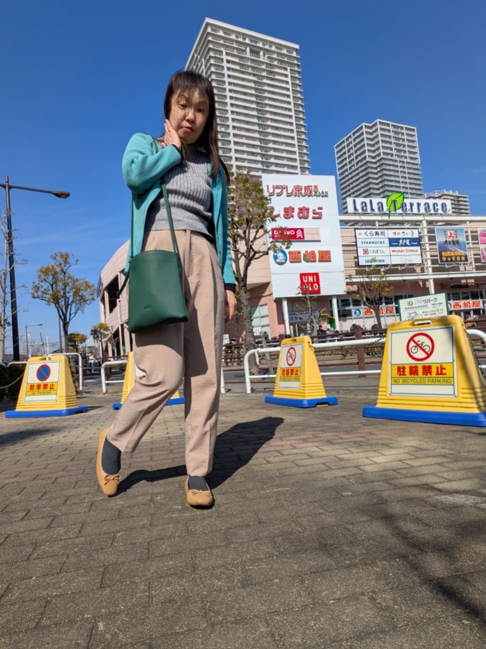 グレー系のニット/セーター、ブルー系のカーディガン/ボレロ、ブルー系のトレンチコートを着用したレディースの春コーディネートの2枚目の写真