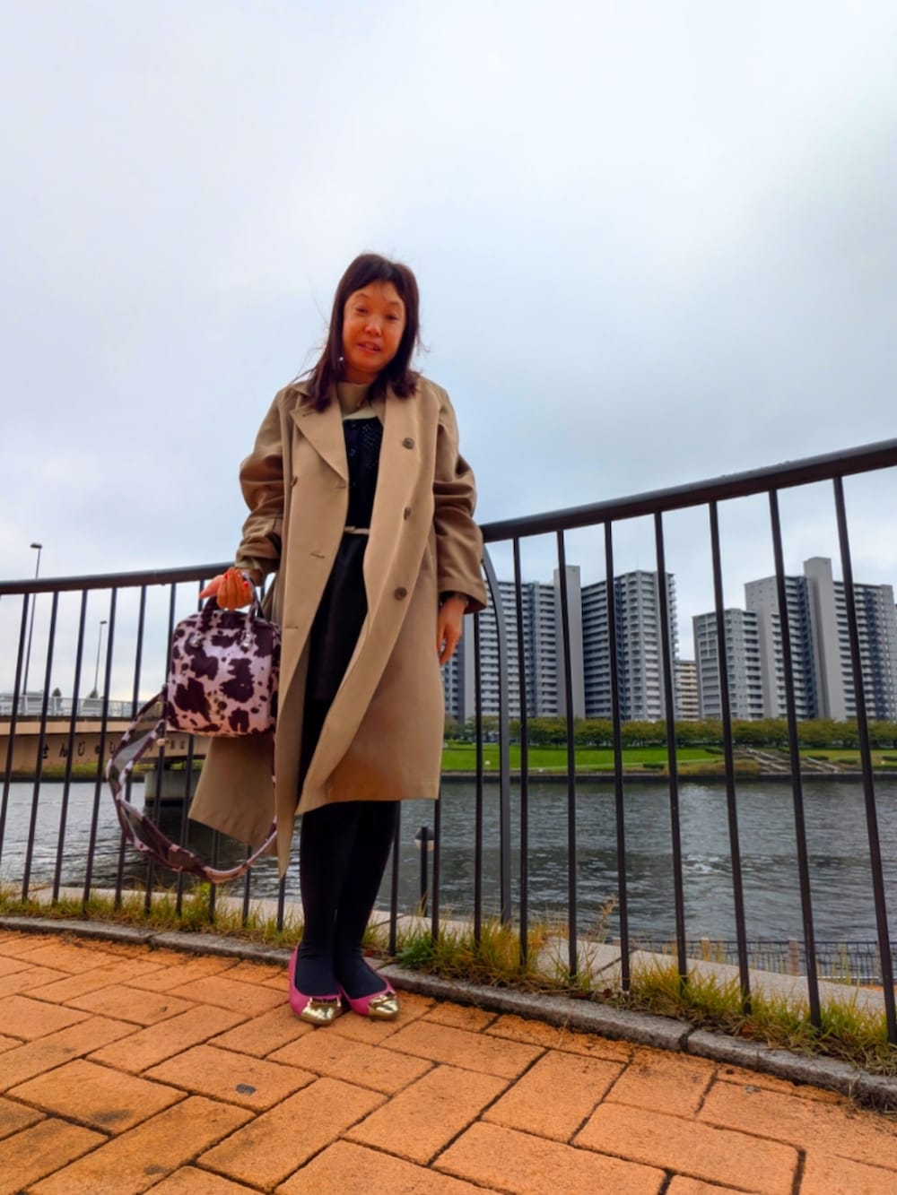 ベージュ系のニット/セーター、ベージュ系のトレンチコート、ブラウン系のスカートを着用したレディースの秋コーディネートの2枚目の写真