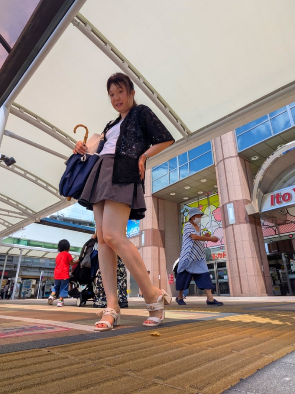 グレー系のスカート、ホワイト系のタンクトップ、ホワイト系のサンダルを着用したレディースの夏コーディネートの2枚目の写真