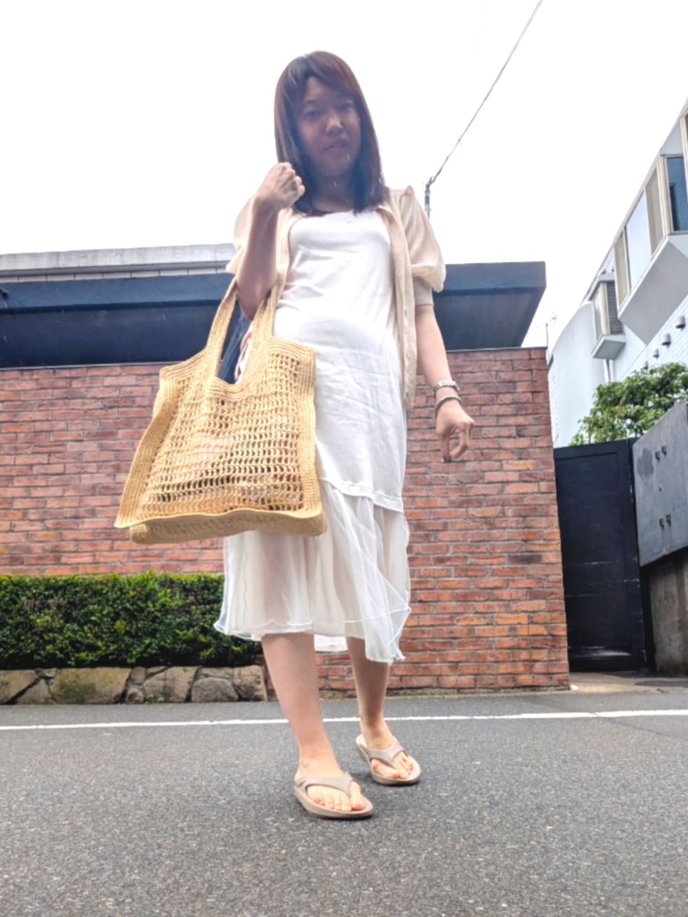 ピンク系のニット/セーター、ベージュ系のバッグ、ホワイト系のワンピース/ドレスを着用したレディースの夏コーディネートの2枚目の写真