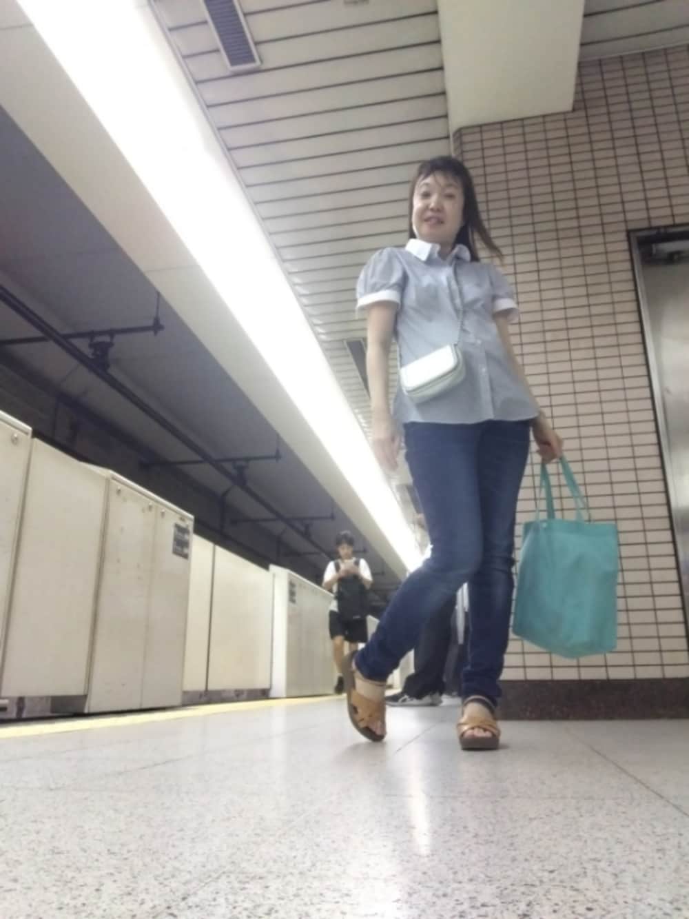 ホワイト系のトップス、ブルー系のパンツ、シルバー系のショルダーバッグを着用したレディースの夏コーディネートの2枚目の写真