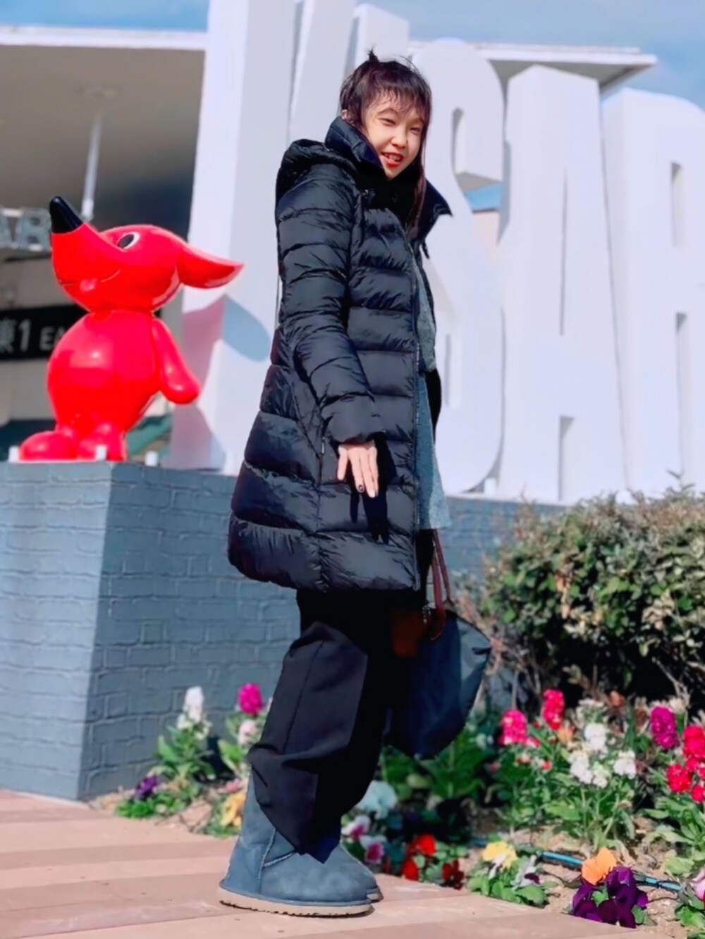 ブラック系のダウンジャケット/コート、グレー系のニット/セーター、グレー系のスカートを着用したレディースの冬コーディネートの2枚目の写真