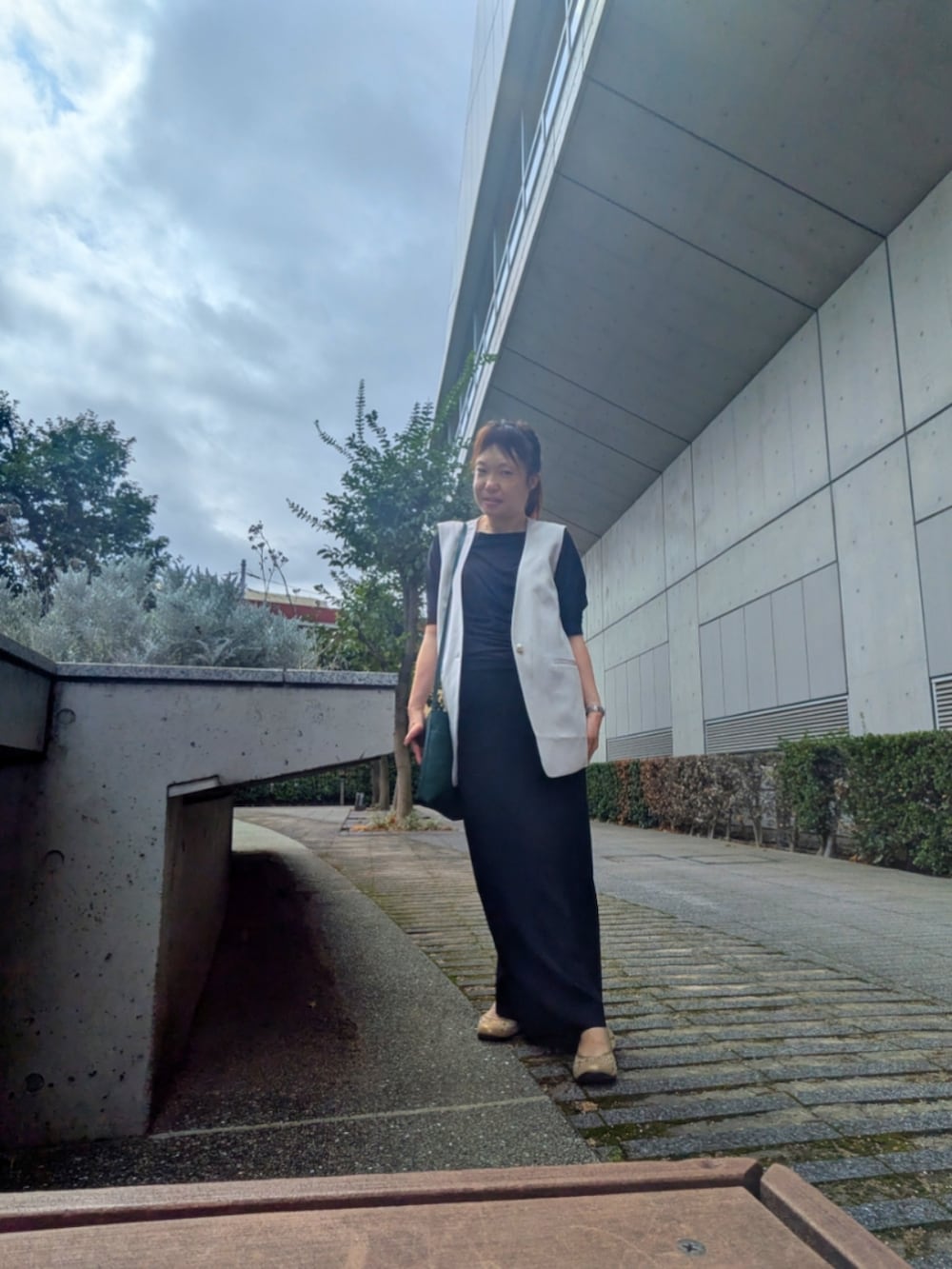 グレー系のベスト、ブラック系のスカート、ブラック系のニット/セーターを着用したレディースの秋コーディネートの2枚目の写真