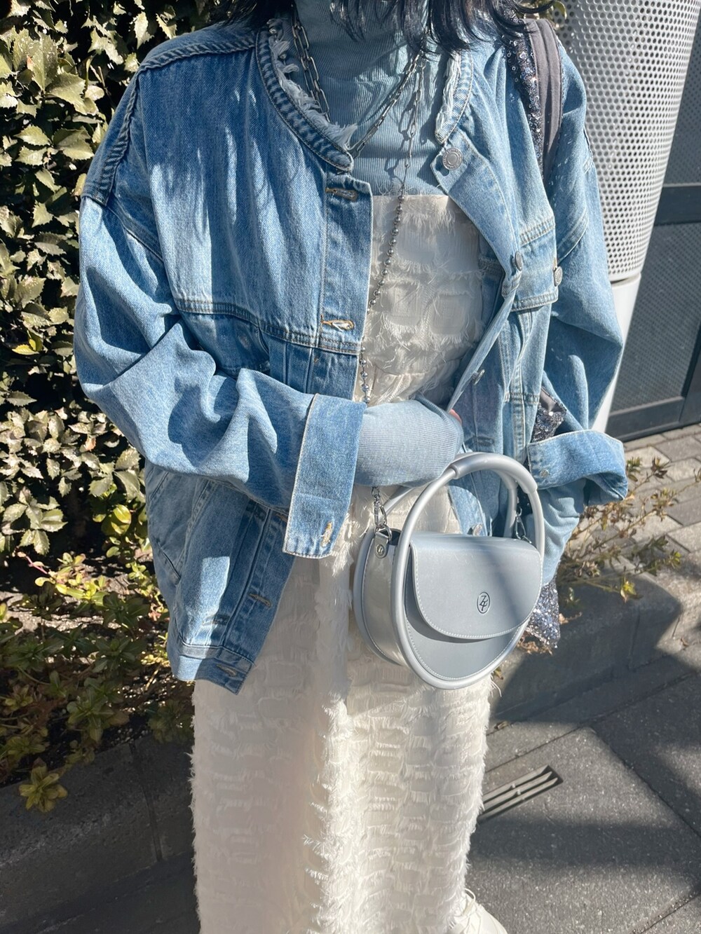 ブルー系のデニムジャケット、ホワイト系のワンピース、ブルー系のTシャツ/カットソーを着用したレディースの春コーディネートの2枚目の写真
