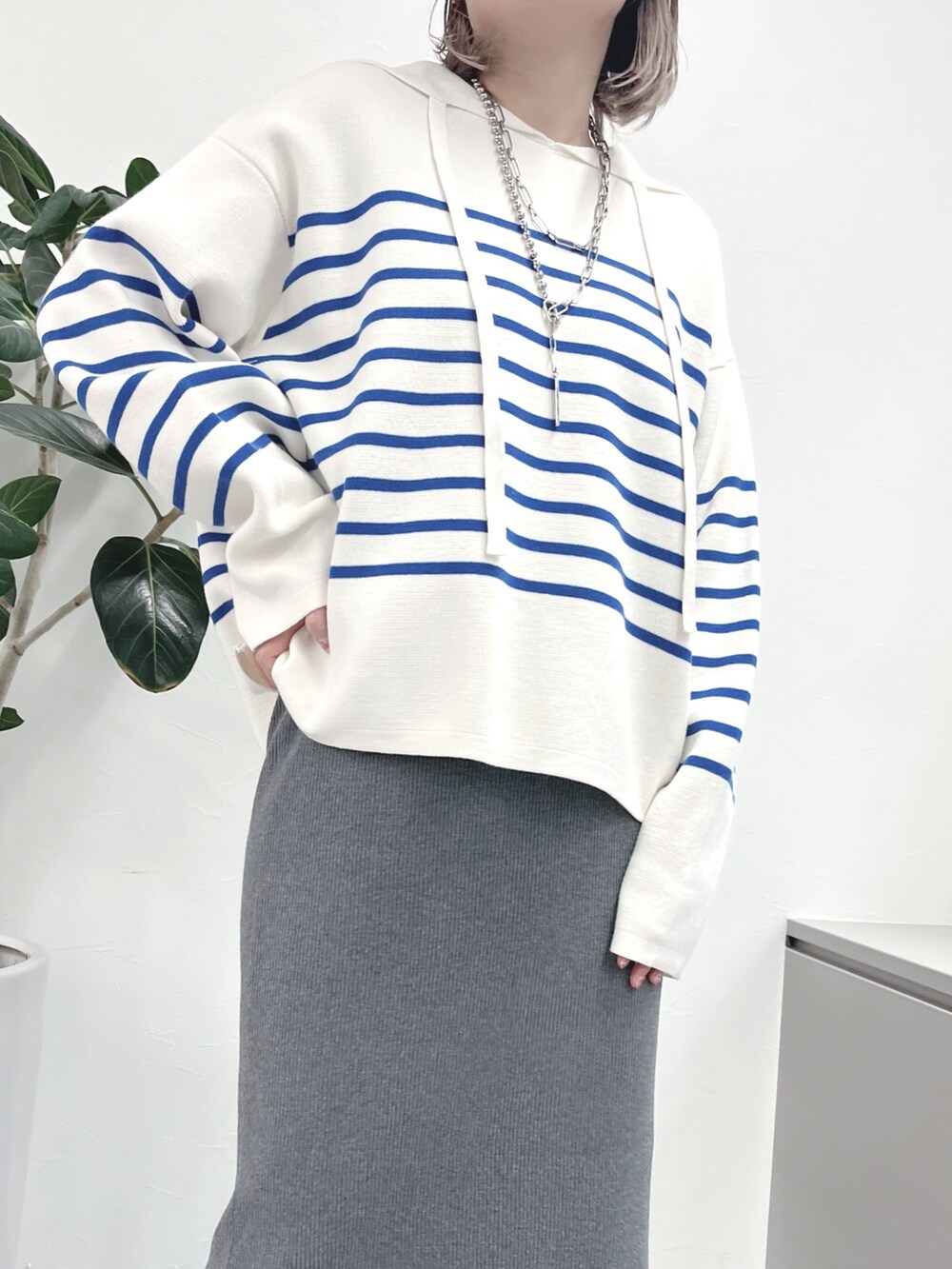 ブルー系のニット/セーター、グレー系のスカート、ブルー系のキャップを着用したレディースの春コーディネートの2枚目の写真