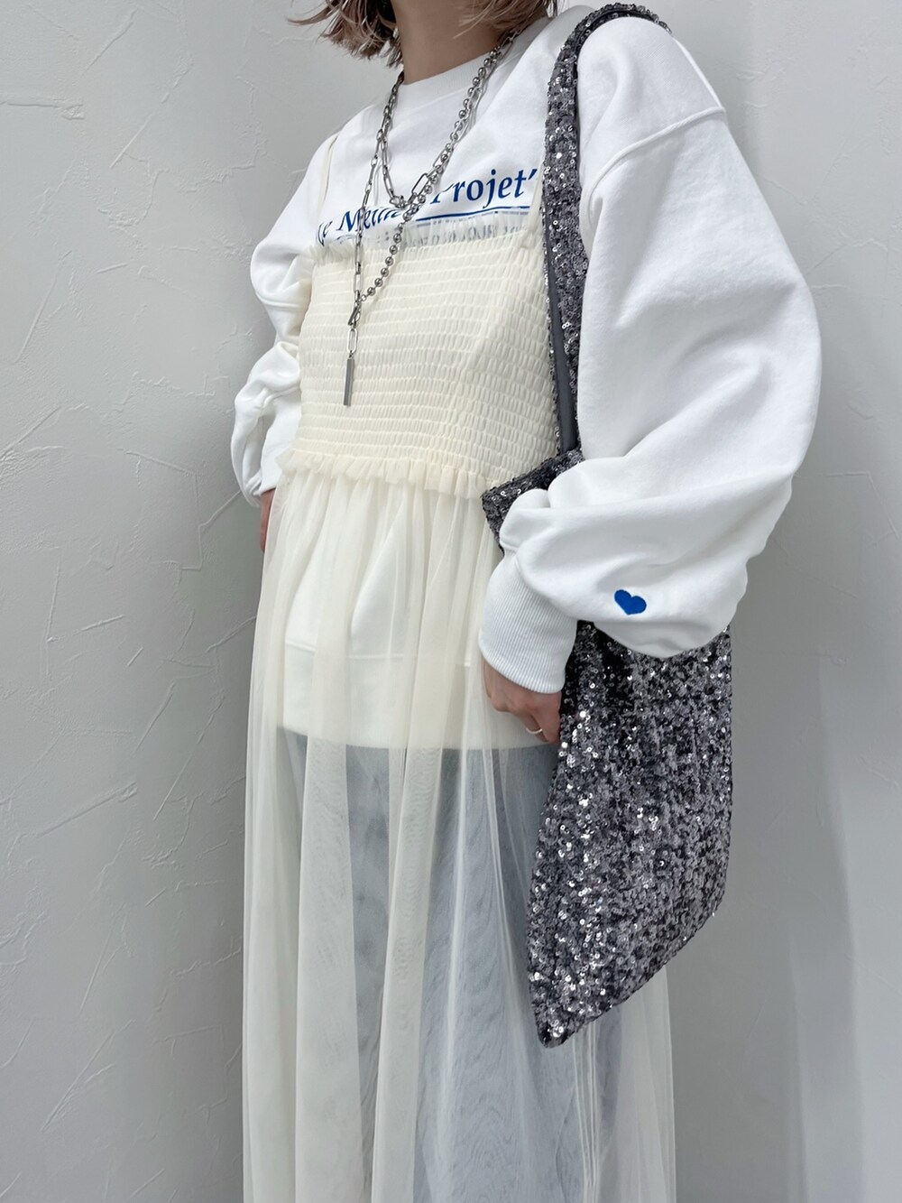 ホワイト系のワンピース、ブルー系のデニムパンツ、ホワイト系のスウェットを着用したレディースの冬コーディネートの4枚目の写真