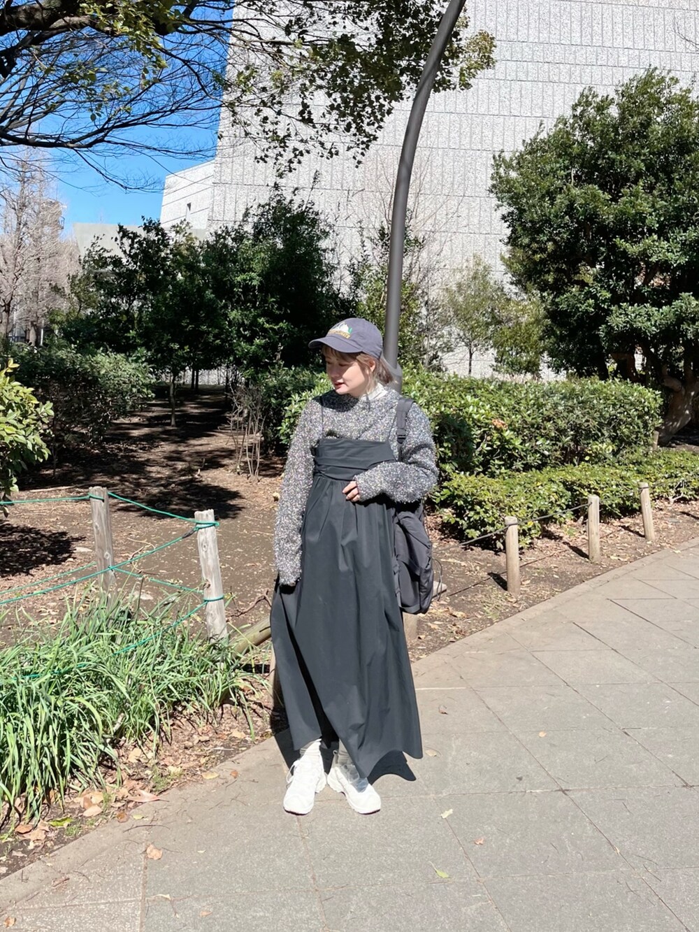 ブラック系のニット/セーター、ブラック系のバックパック/リュック、ブラック系のワンピースを着用したレディースの春コーディネートの2枚目の写真