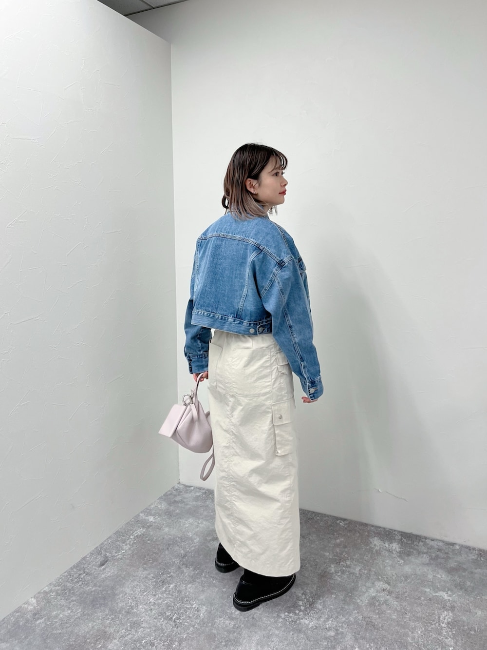 ブルー系のデニムジャケット、シルバー系のシャツ/ブラウス、ベージュ系のスカートを着用したレディースの春コーディネートの3枚目の写真