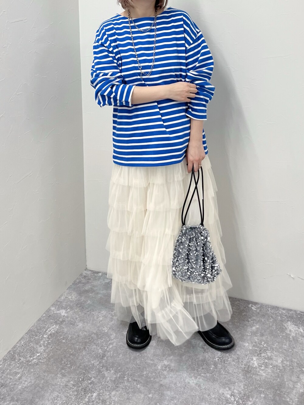 ブルー系のTシャツ/カットソー、ホワイト系のスカート、グレー系のショルダーバッグを着用したレディースの春コーディネートの2枚目の写真