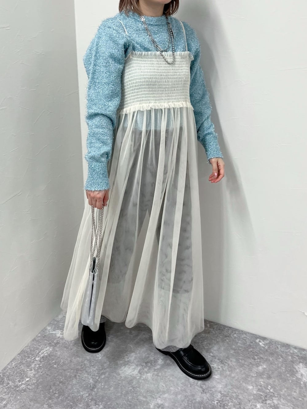 ホワイト系のワンピース、ブルー系のニット/セーター、ブラック系のデニムパンツを着用したレディースの冬コーディネートの2枚目の写真