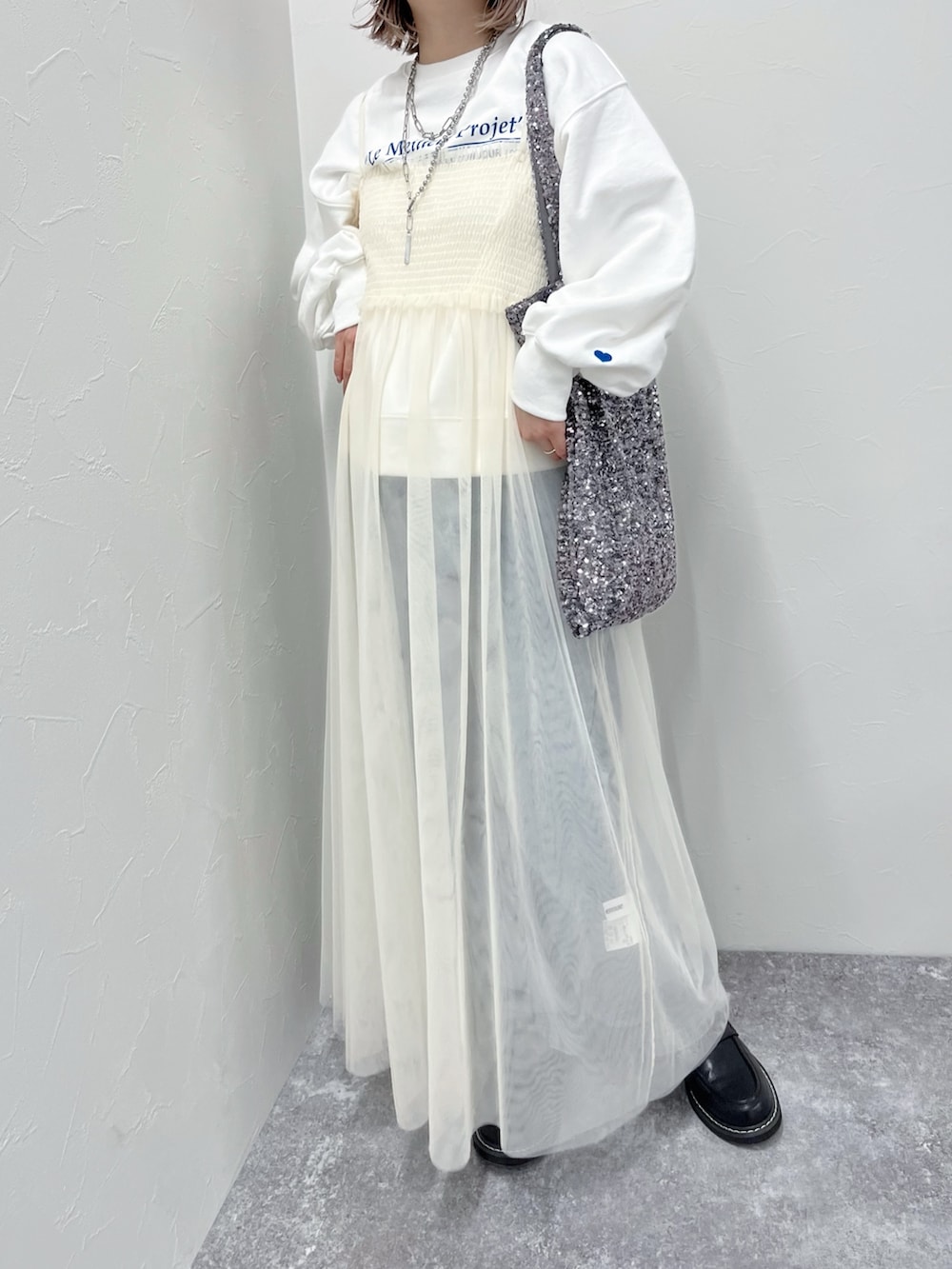 ホワイト系のワンピース、ブルー系のデニムパンツ、ホワイト系のスウェットを着用したレディースの冬コーディネートの2枚目の写真