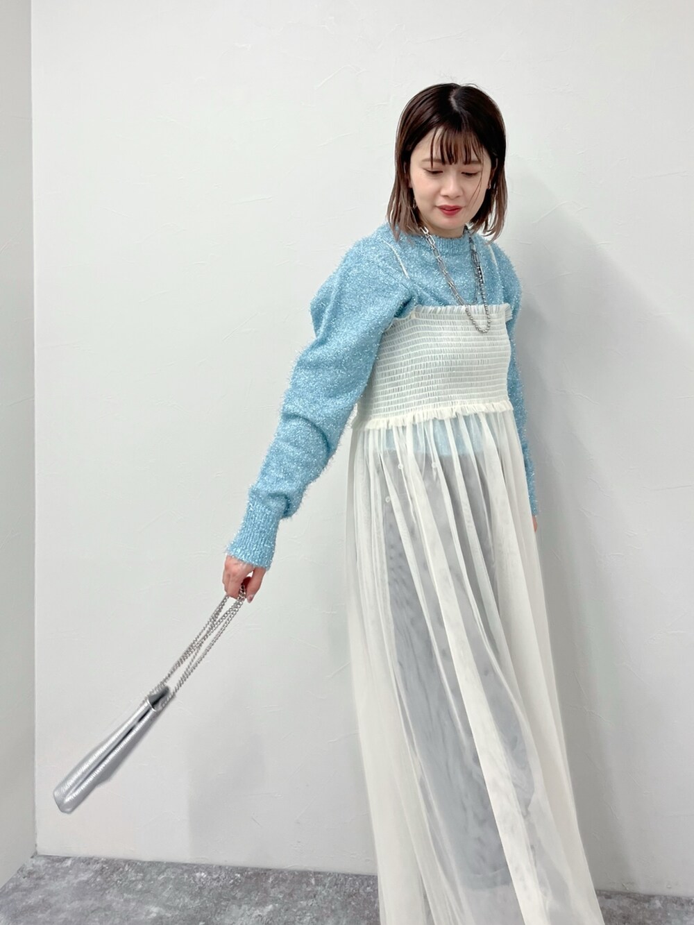 ホワイト系のワンピース、ブルー系のニット/セーター、ブラック系のデニムパンツを着用したレディースの冬コーディネートの4枚目の写真