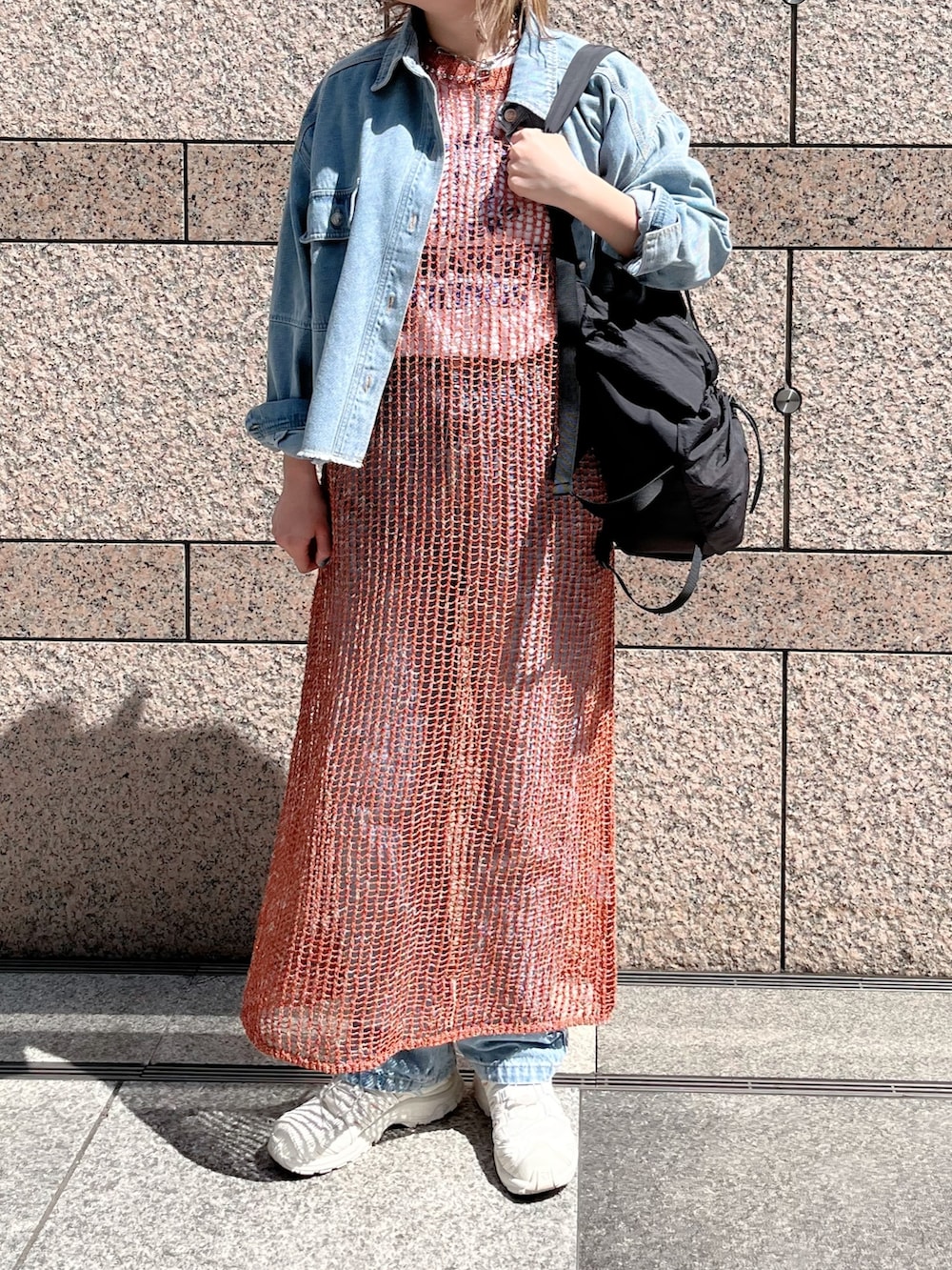 ブラウン系のニット/セーター、ブルー系のシャツ/ブラウス、ブラック系のバックパック/リュックを着用したレディースの春コーディネートの2枚目の写真