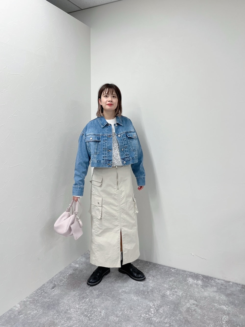 ブルー系のデニムジャケット、シルバー系のシャツ/ブラウス、ベージュ系のスカートを着用したレディースの春コーディネートの5枚目の写真