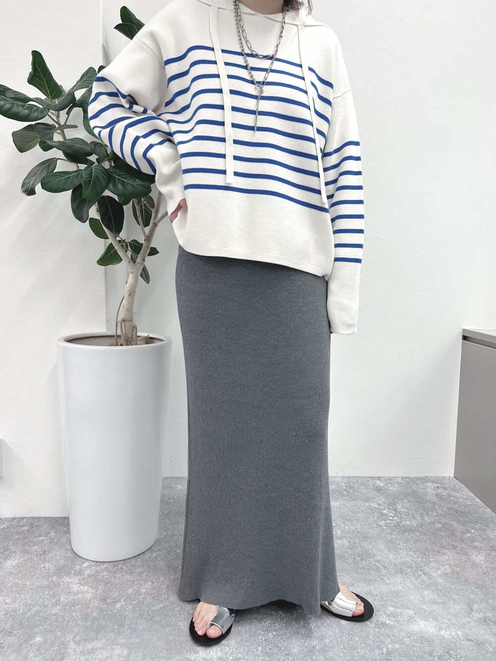 ブルー系のニット/セーター、グレー系のスカート、ブルー系のキャップを着用したレディースの春コーディネートの3枚目の写真