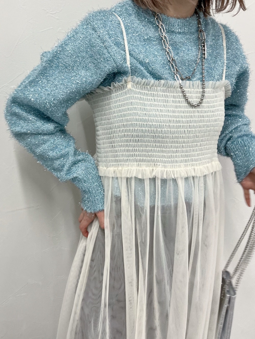 ホワイト系のワンピース、ブルー系のニット/セーター、ブラック系のデニムパンツを着用したレディースの冬コーディネートの3枚目の写真