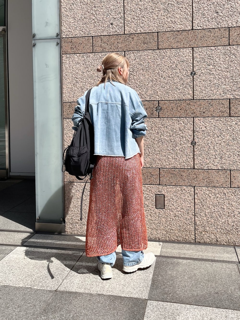 ブラウン系のニット/セーター、ブルー系のシャツ/ブラウス、ブラック系のバックパック/リュックを着用したレディースの春コーディネートの3枚目の写真