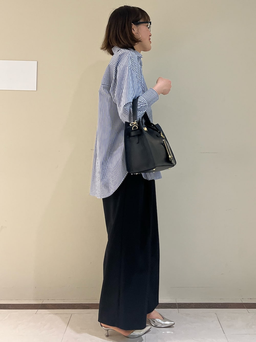 ブラック系のその他パンツ、ブルー系のシャツ/ブラウス、ブラック系のショルダーバッグを着用したレディースの春コーディネートの5枚目の写真
