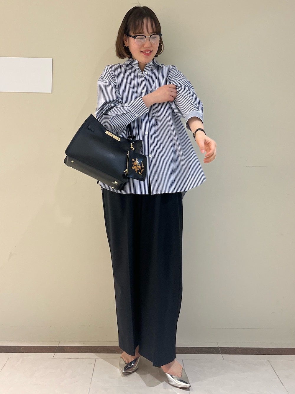 ブラック系のその他パンツ、ブルー系のシャツ/ブラウス、ブラック系のショルダーバッグを着用したレディースの春コーディネートの2枚目の写真