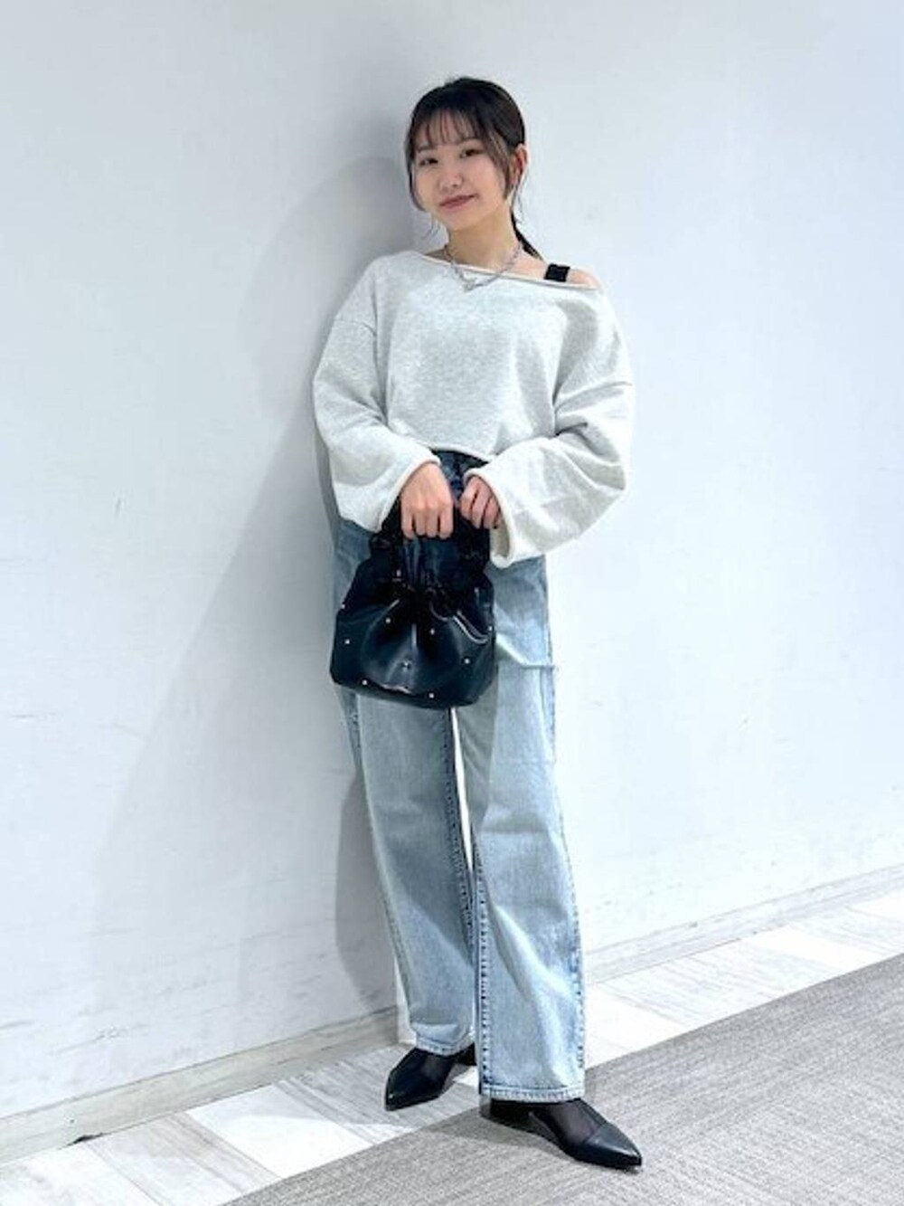 ブラック系のハンドバッグ、ブラック系のタンクトップ、ブルー系のデニムパンツを着用したレディースの冬コーディネートの2枚目の写真