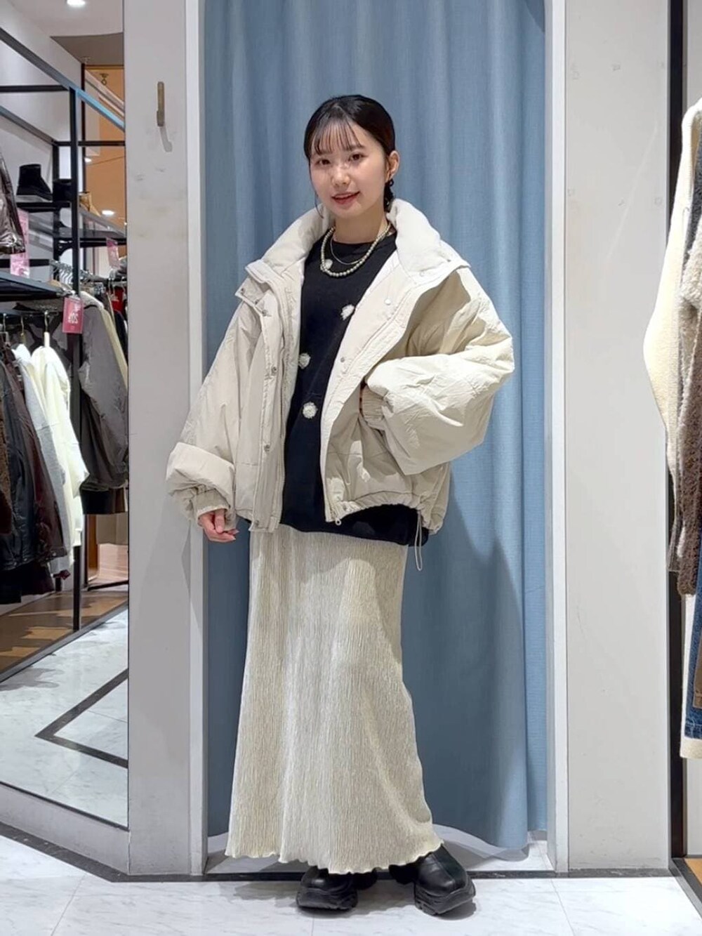 ホワイト系のその他アウター、ブラック系のブーツ、ホワイト系のスカートを着用したレディースの冬コーディネートの2枚目の写真