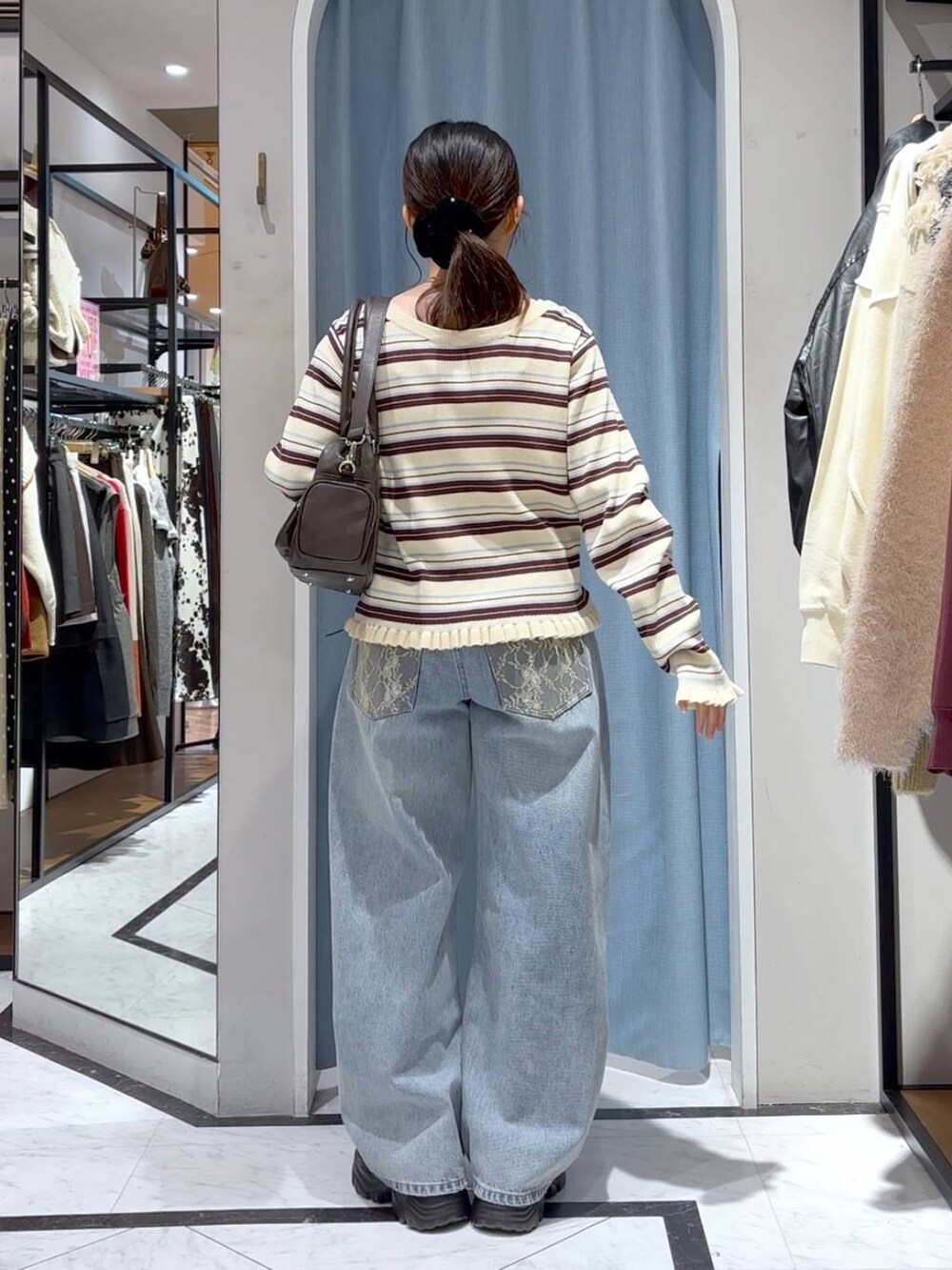 ブルー系のデニムパンツ、ブラウン系のボストンバッグ、ブラウン系のローファーを着用したレディースの冬コーディネートの6枚目の写真