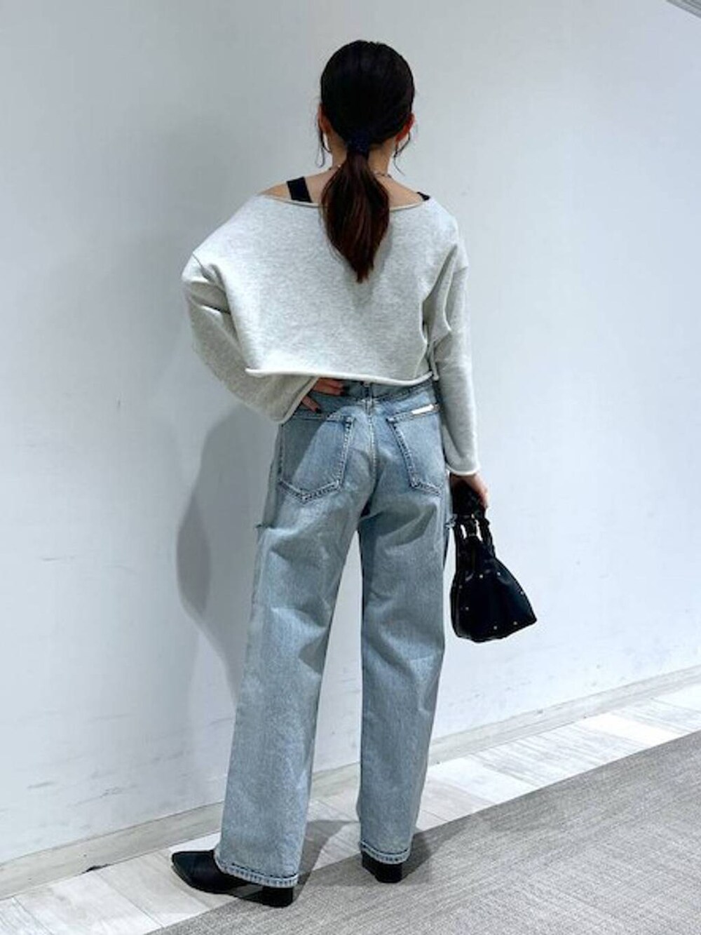 ブラック系のハンドバッグ、ブラック系のタンクトップ、ブルー系のデニムパンツを着用したレディースの冬コーディネートの7枚目の写真