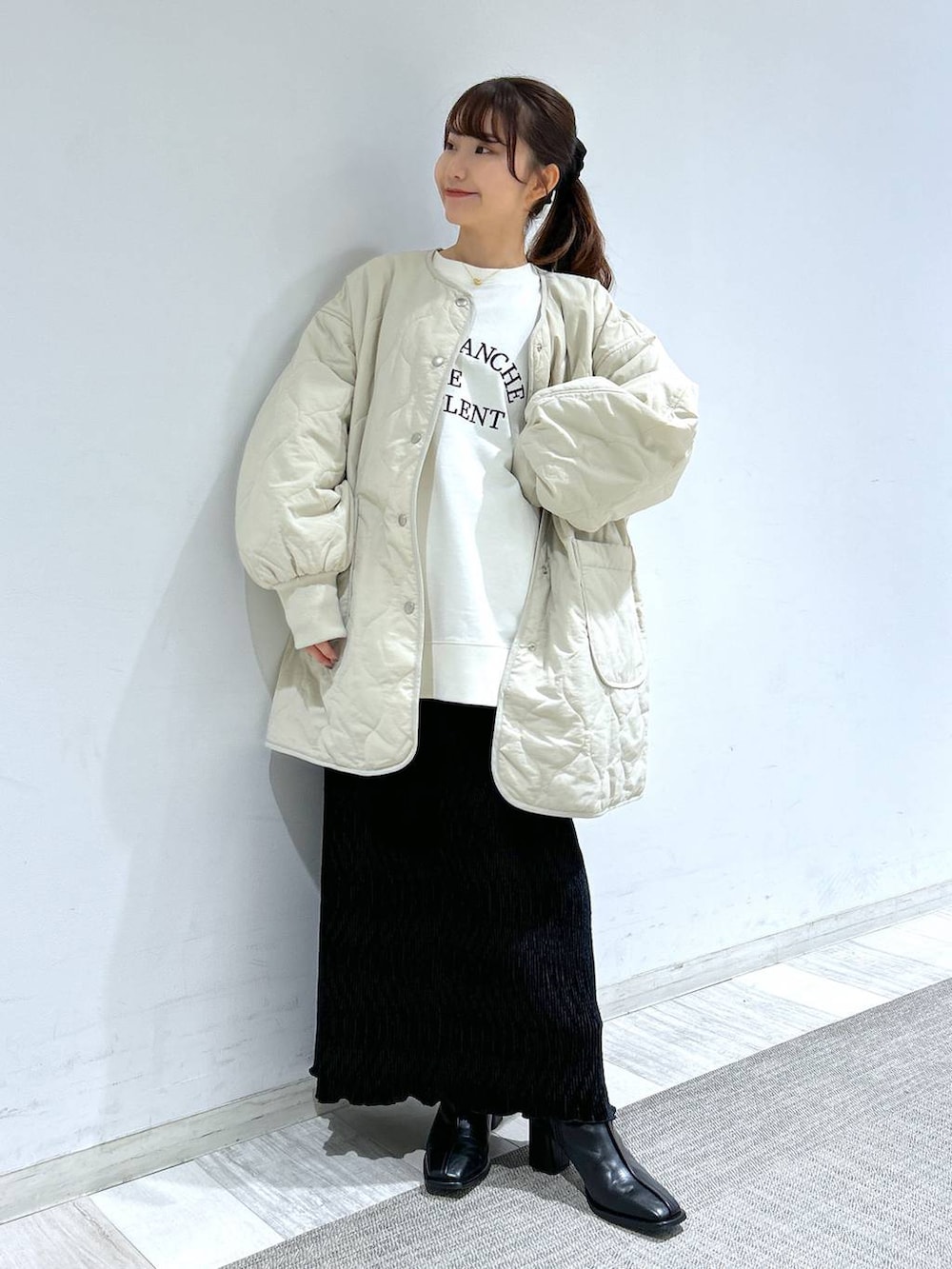 ホワイト系のブルゾン、ブラック系のパンプス、ブラック系のスカートを着用したレディースの冬コーディネートの7枚目の写真