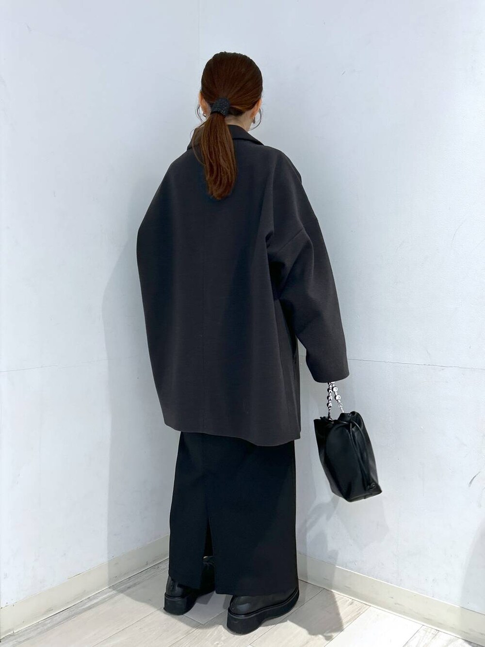 グレー系のステンカラーコート、ブラック系のブーツ、ブルー系のニット/セーターを着用したレディースの冬コーディネートの7枚目の写真