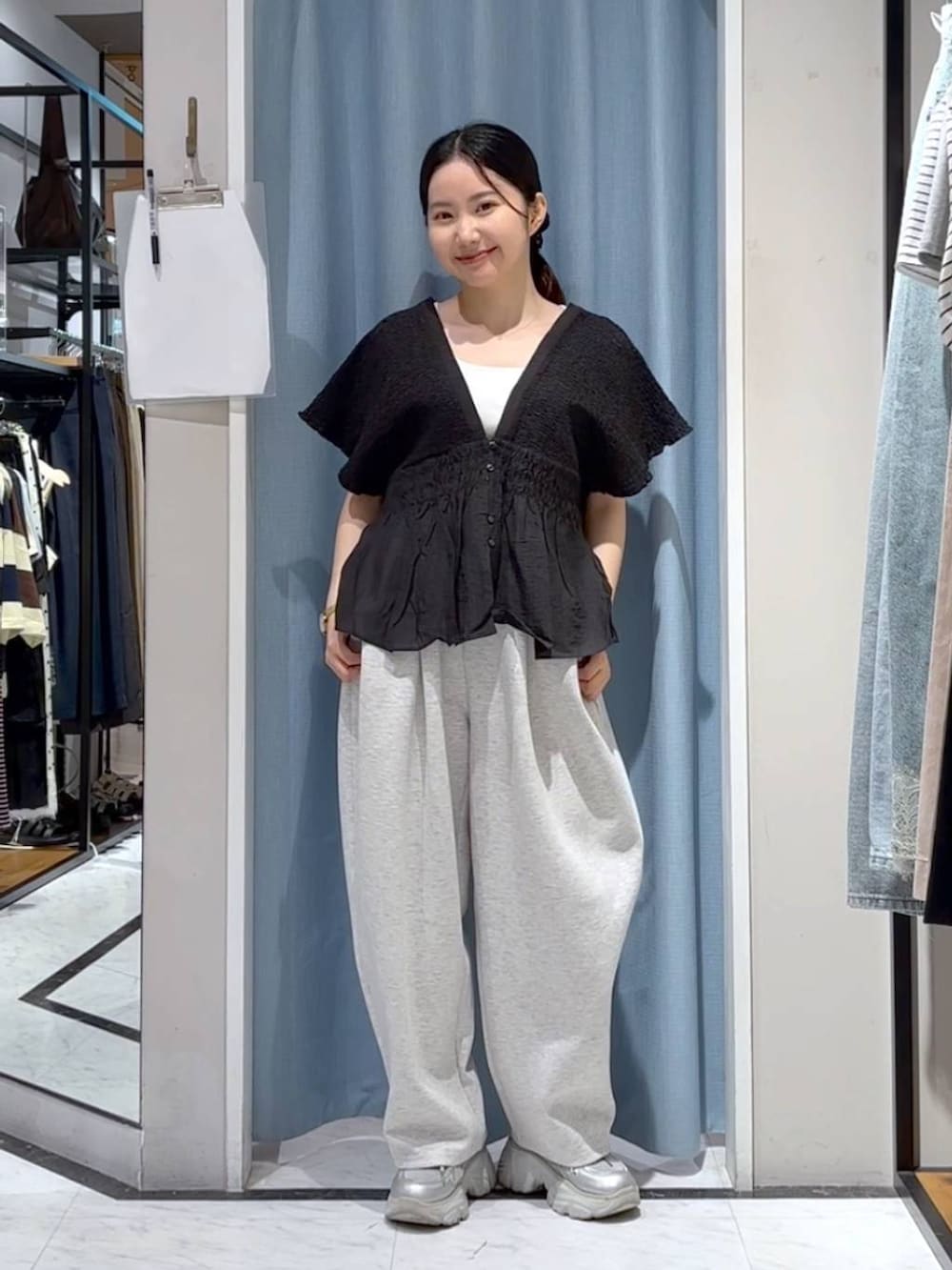 グレー系のスウェットパンツ、ブラック系のシャツ/ブラウス、シルバー系のスニーカーを着用したレディースの夏コーディネートの2枚目の写真