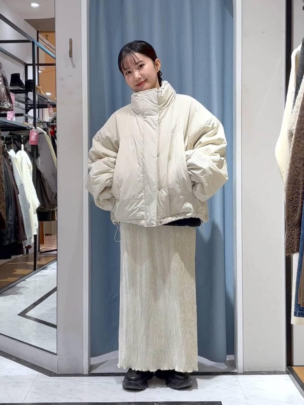 ホワイト系のその他アウター、ブラック系のブーツ、ホワイト系のスカートを着用したレディースの冬コーディネートの3枚目の写真