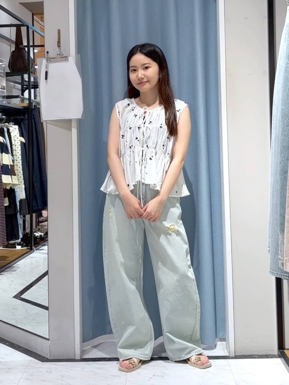ブルー系のデニムパンツ、ホワイト系のサンダル、ホワイト系のシャツ/ブラウスを着用したレディースの夏コーディネートの4枚目の写真