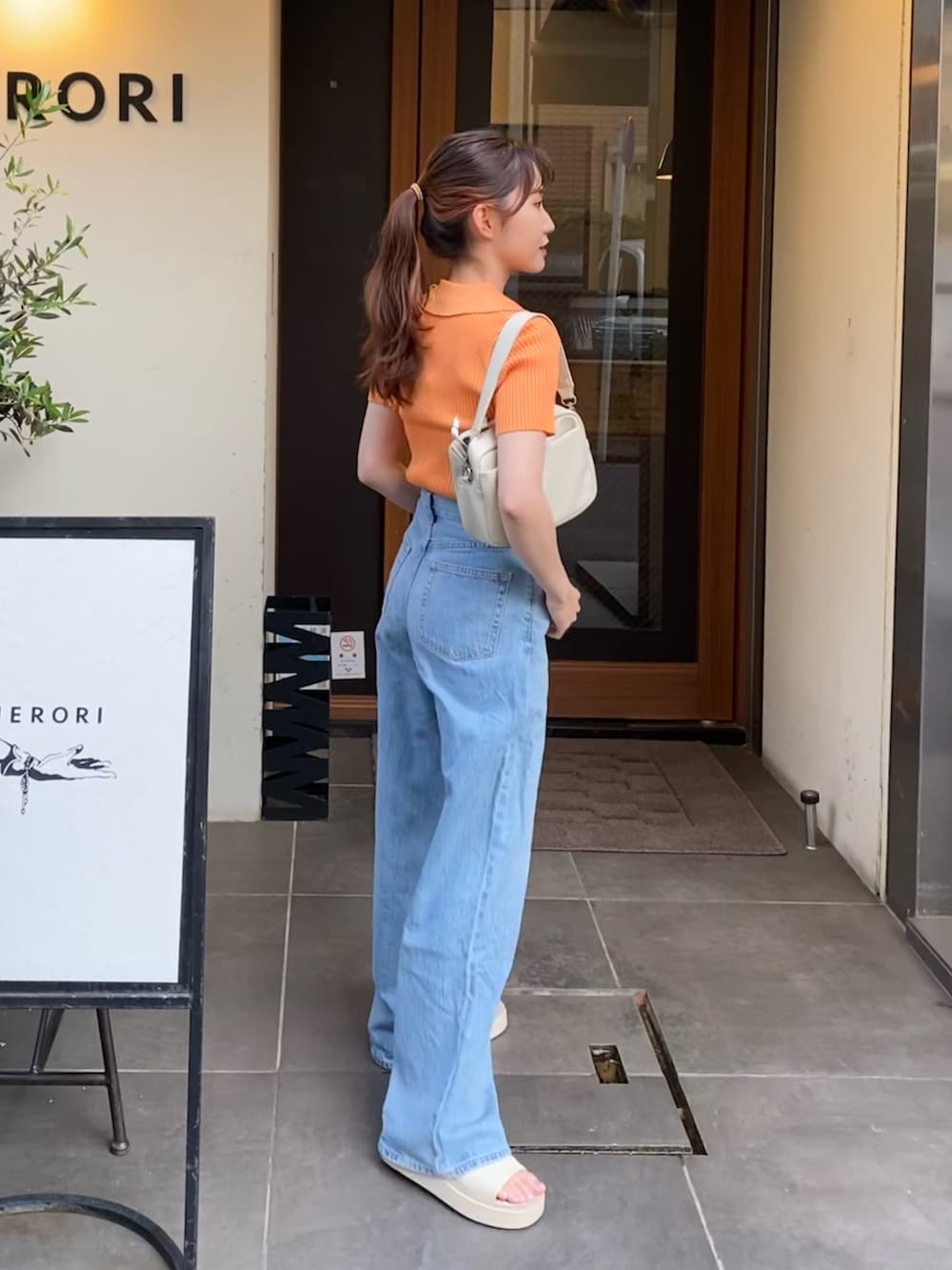 ブルー系のデニムパンツ、オレンジ系のTシャツ/カットソー、ホワイト系のサンダルを着用したレディースの夏コーディネートの2枚目の写真