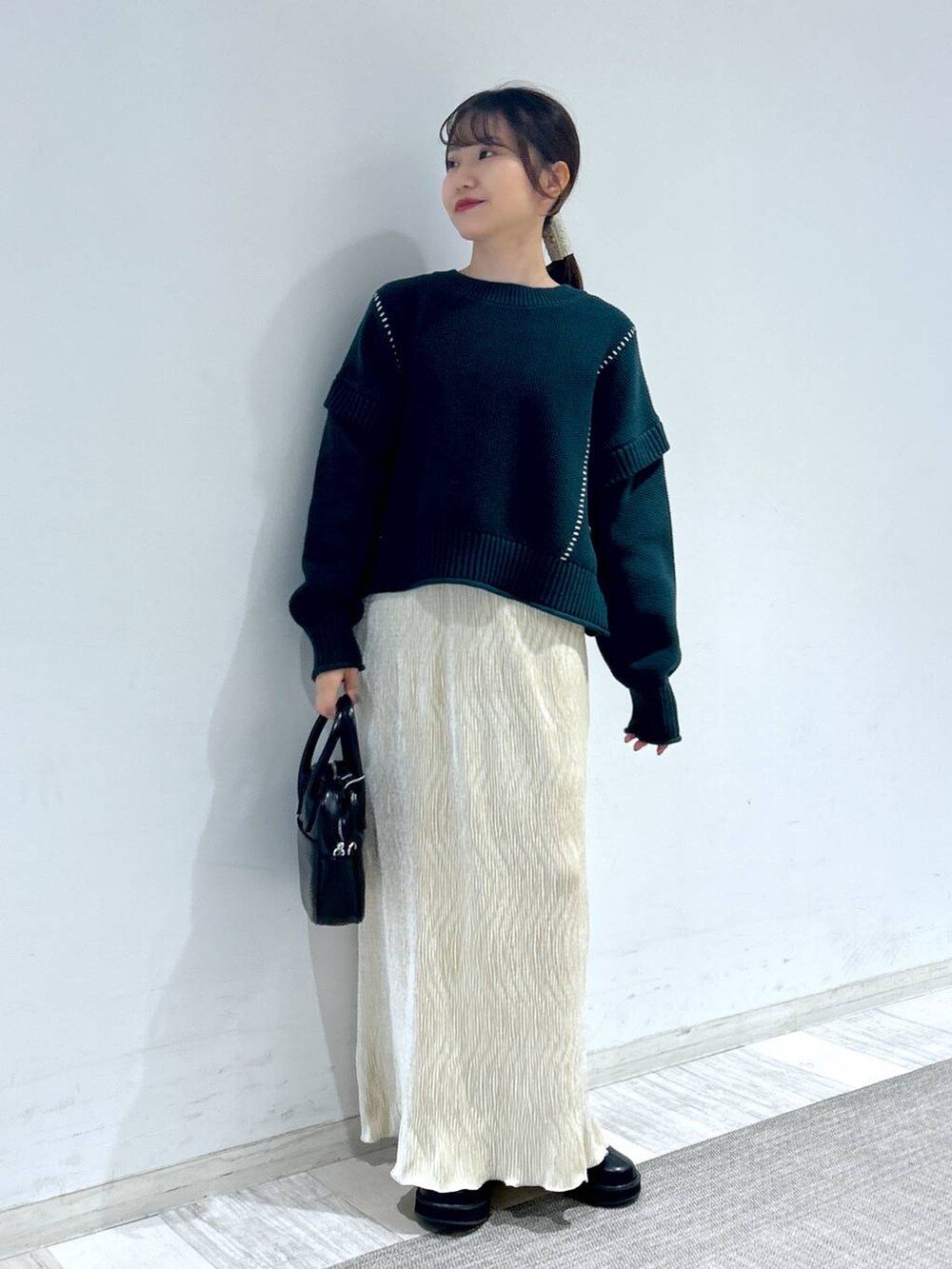 グリーン系のTシャツ/カットソー、ブラック系のブーツ、ブラック系のボストンバッグを着用したレディースの秋コーディネートの7枚目の写真