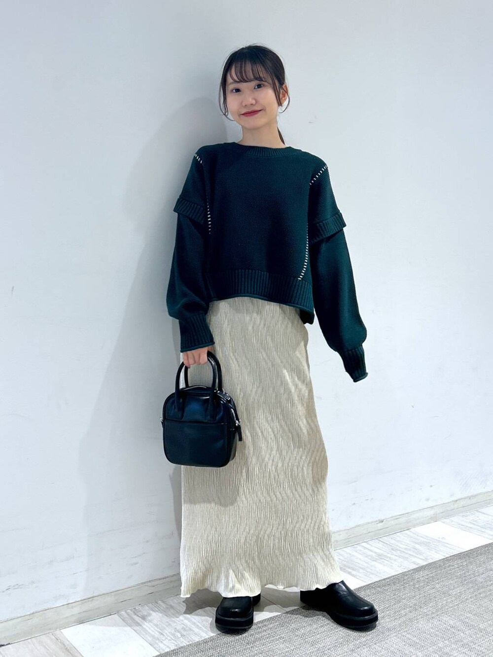 グリーン系のTシャツ/カットソー、ブラック系のブーツ、ブラック系のボストンバッグを着用したレディースの秋コーディネートの2枚目の写真