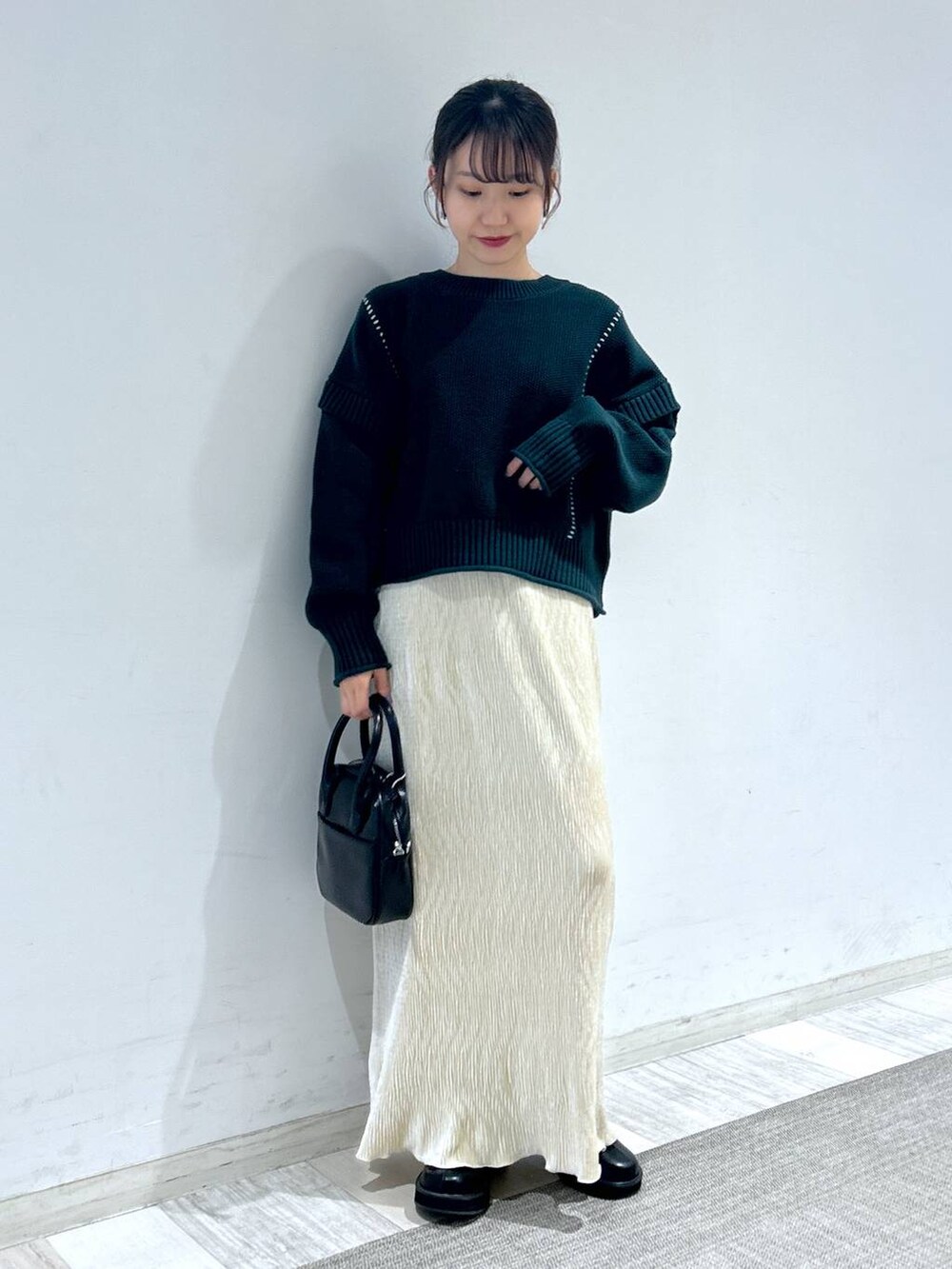 グリーン系のTシャツ/カットソー、ブラック系のブーツ、ブラック系のボストンバッグを着用したレディースの秋コーディネートの5枚目の写真