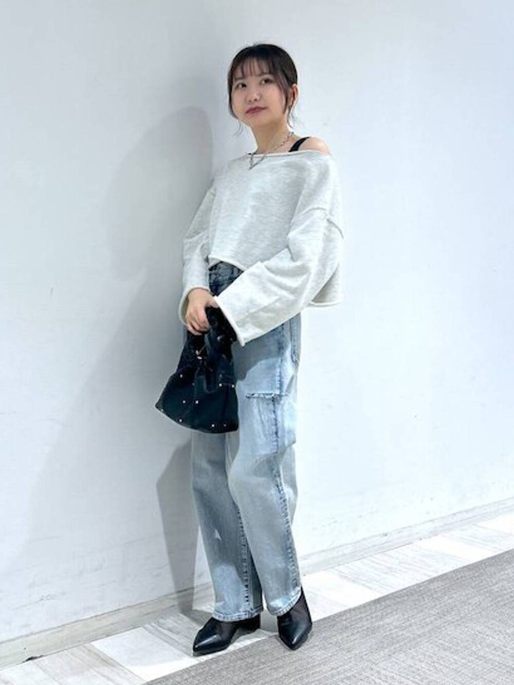 ブラック系のハンドバッグ、ブラック系のタンクトップ、ブルー系のデニムパンツを着用したレディースの冬コーディネートの4枚目の写真