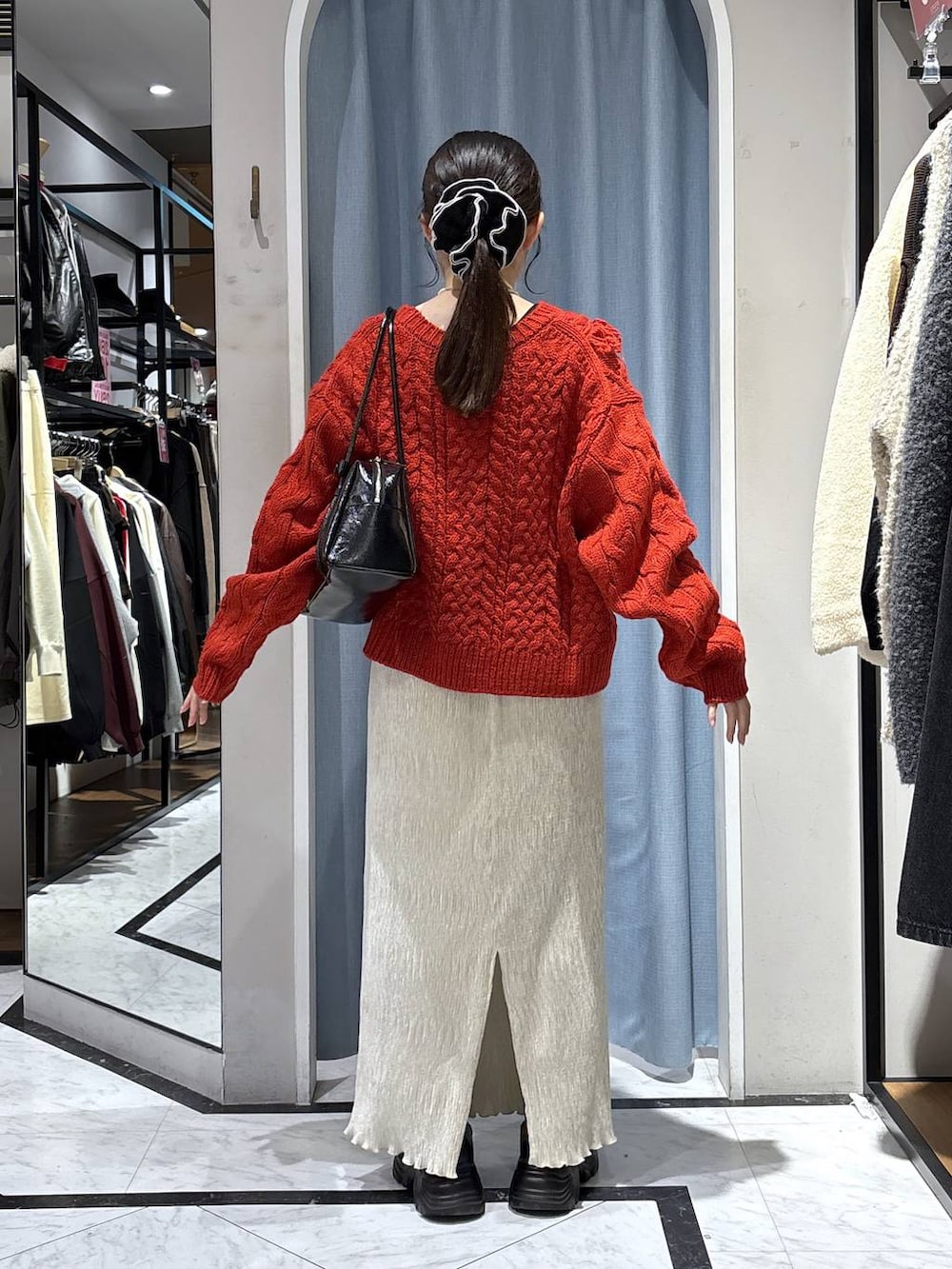 ブラック系のブーツ、レッド系のポロシャツ、ホワイト系のスカートを着用したレディースの冬コーディネートの4枚目の写真