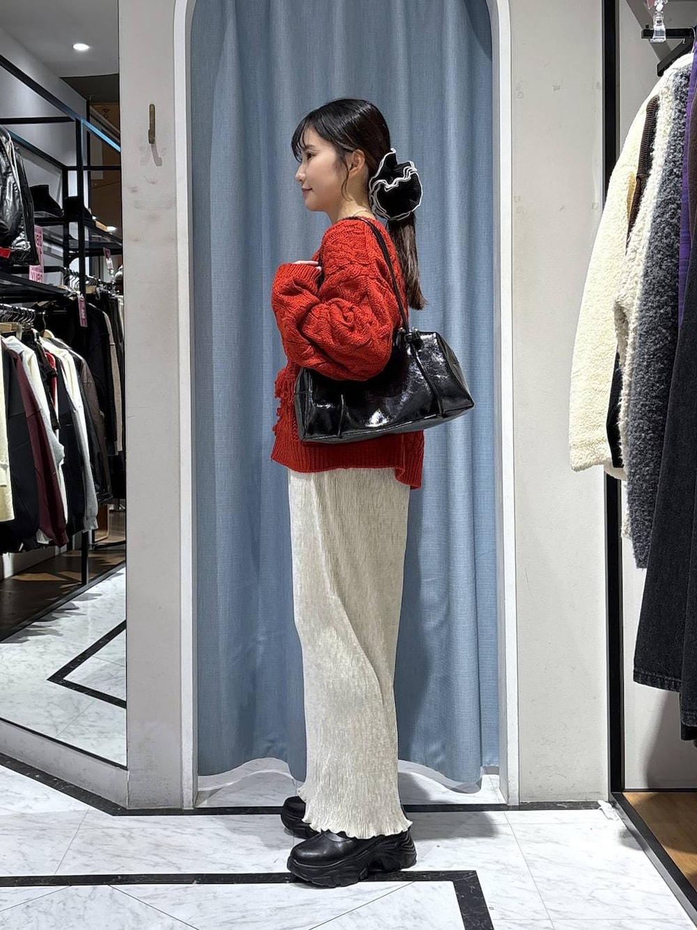 ブラック系のブーツ、レッド系のポロシャツ、ホワイト系のスカートを着用したレディースの冬コーディネートの3枚目の写真