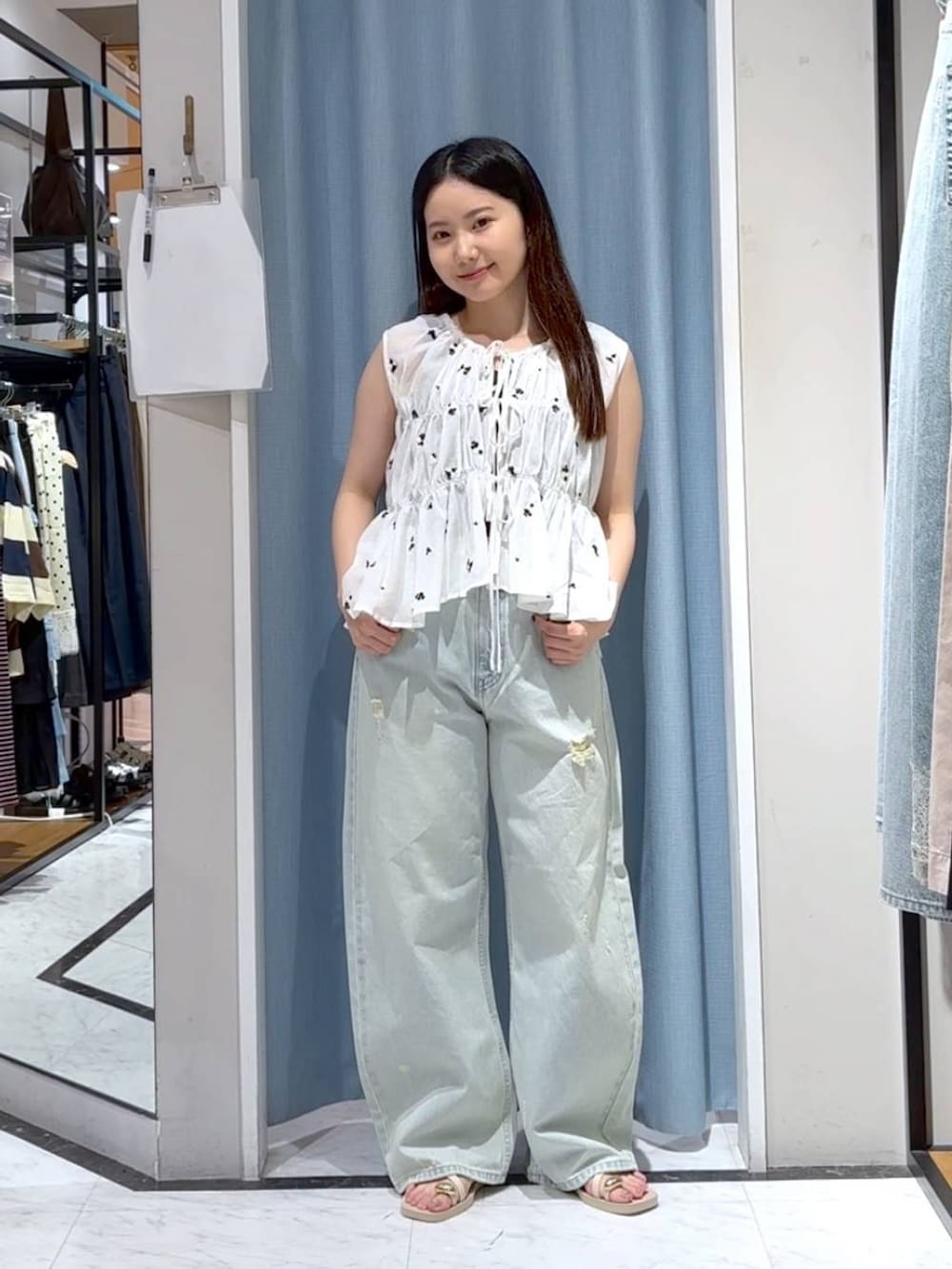 ブルー系のデニムパンツ、ホワイト系のサンダル、ホワイト系のシャツ/ブラウスを着用したレディースの夏コーディネートの2枚目の写真