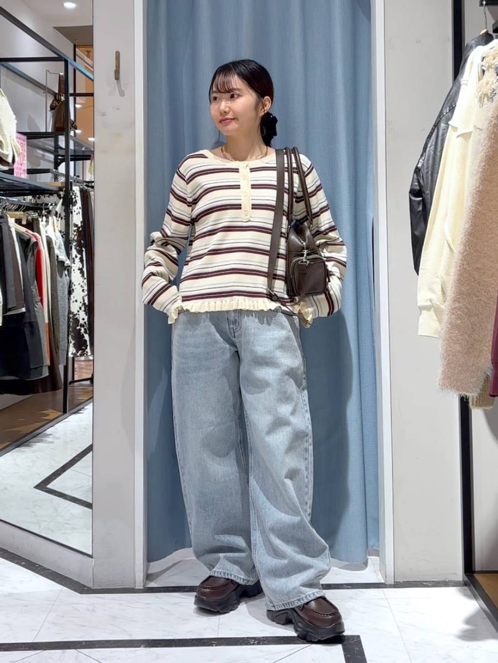 ブルー系のデニムパンツ、ブラウン系のボストンバッグ、ブラウン系のローファーを着用したレディースの冬コーディネートの2枚目の写真