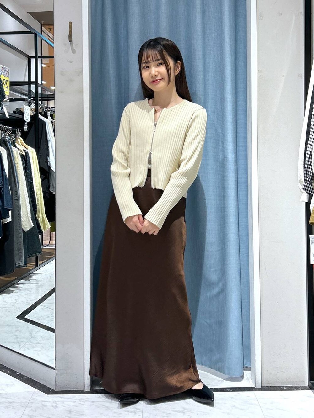 ホワイト系のカーディガン/ボレロ、ブラック系のパンプス、ゴールド系のタンクトップを着用したレディースの春コーディネートの5枚目の写真