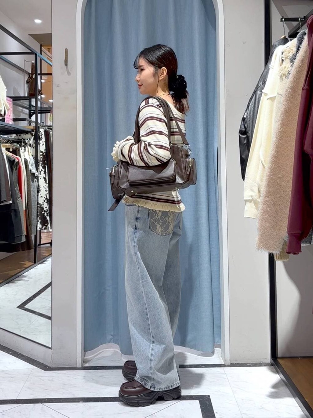 ブルー系のデニムパンツ、ブラウン系のボストンバッグ、ブラウン系のローファーを着用したレディースの冬コーディネートの5枚目の写真