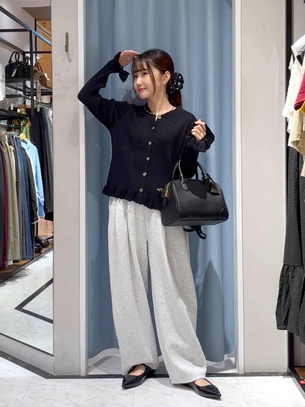 グレー系のスウェットパンツ、ブラック系のショルダーバッグ、ブラック系のニット/セーターを着用したレディースの秋コーディネートの2枚目の写真