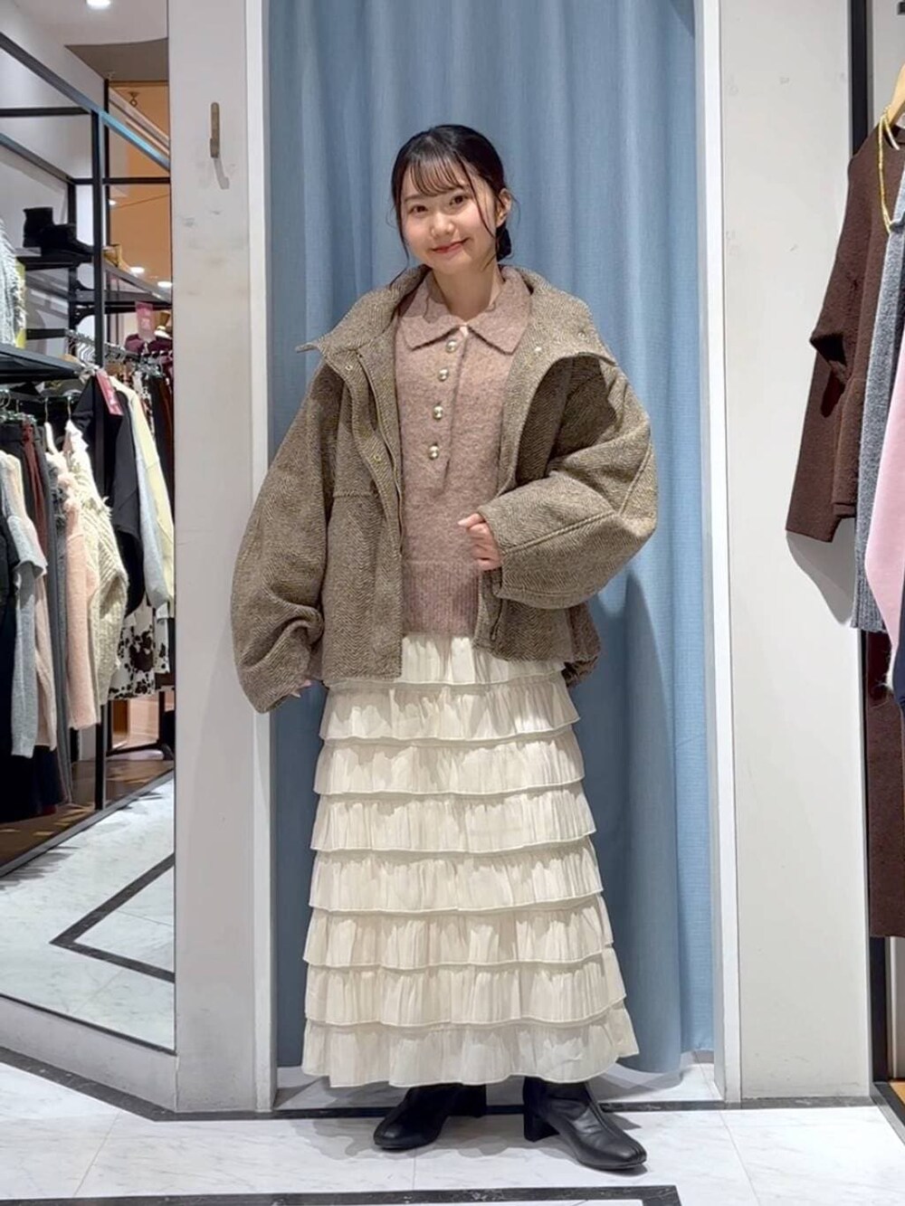 ベージュ系のブルゾン、ホワイト系のスカート、ブラウン系のニット/セーターを着用したレディースの冬コーディネートの3枚目の写真