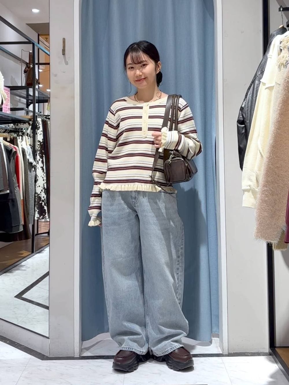 ブルー系のデニムパンツ、ブラウン系のボストンバッグ、ブラウン系のローファーを着用したレディースの冬コーディネートの4枚目の写真