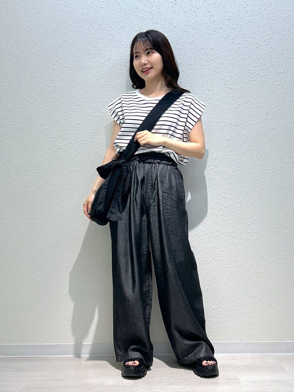 ブラック系のサンダル、ブラック系のデニムパンツ、ブラック系のTシャツ/カットソーを着用したレディースの夏コーディネートの5枚目の写真