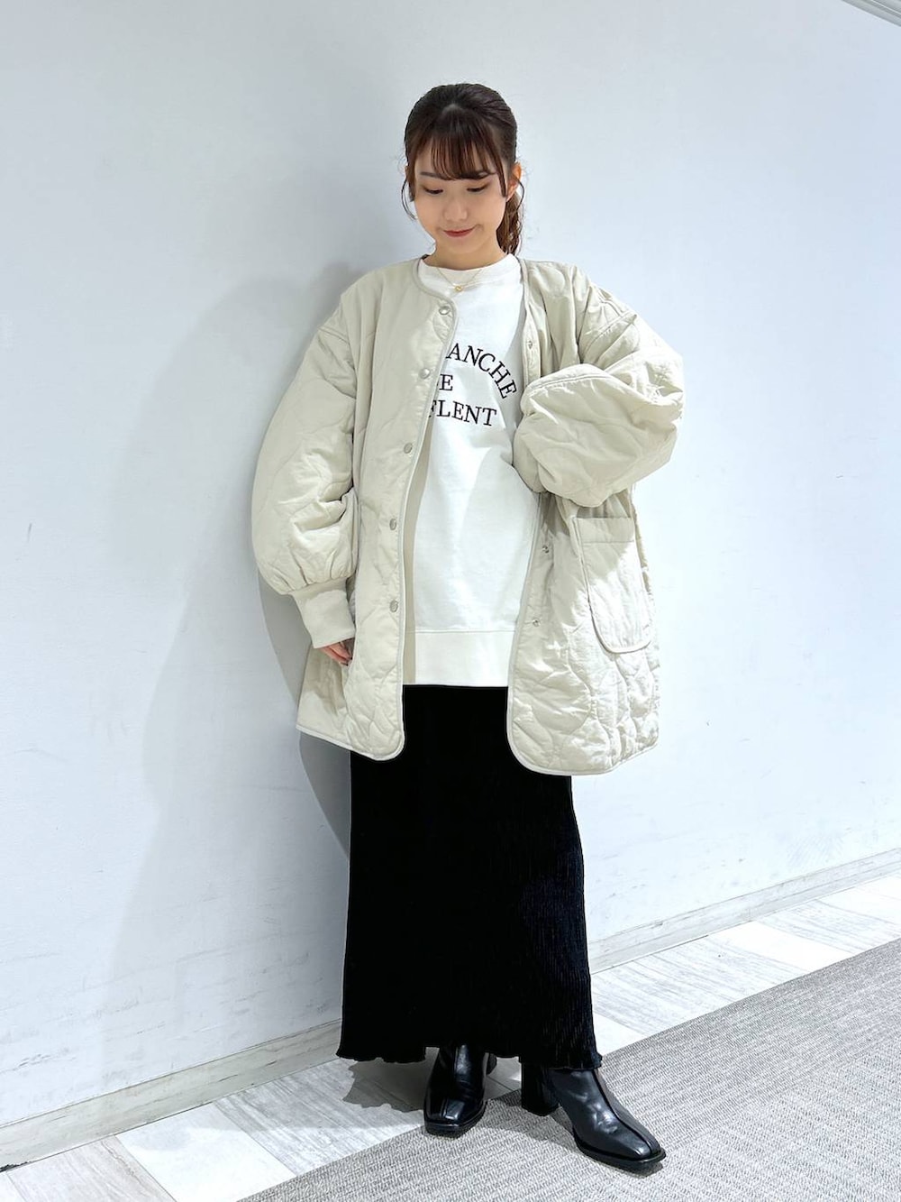 ホワイト系のブルゾン、ブラック系のパンプス、ブラック系のスカートを着用したレディースの冬コーディネートの8枚目の写真