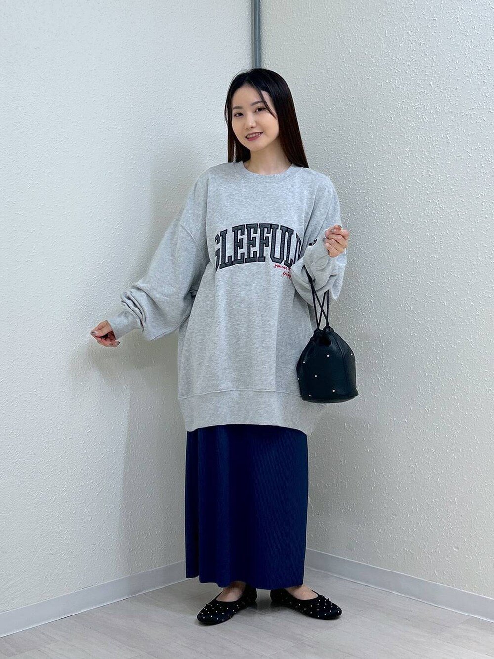 ブラック系のスカート、ブラック系のショルダーバッグ、ブラック系のバレエシューズを着用したレディースの秋コーディネートの3枚目の写真